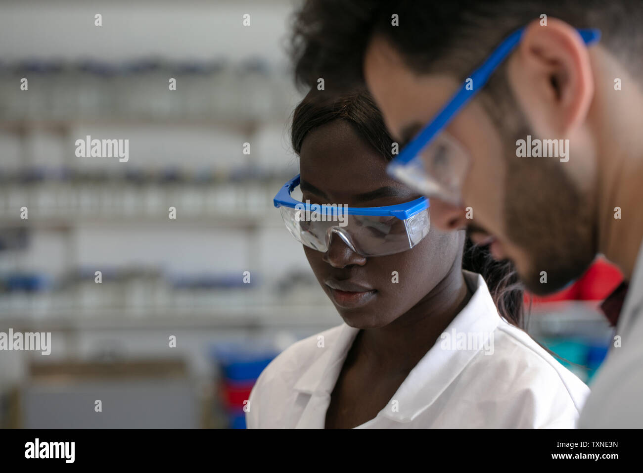 Young male and female scientists wearing protective goggles in laboratory, close up Stock Photo