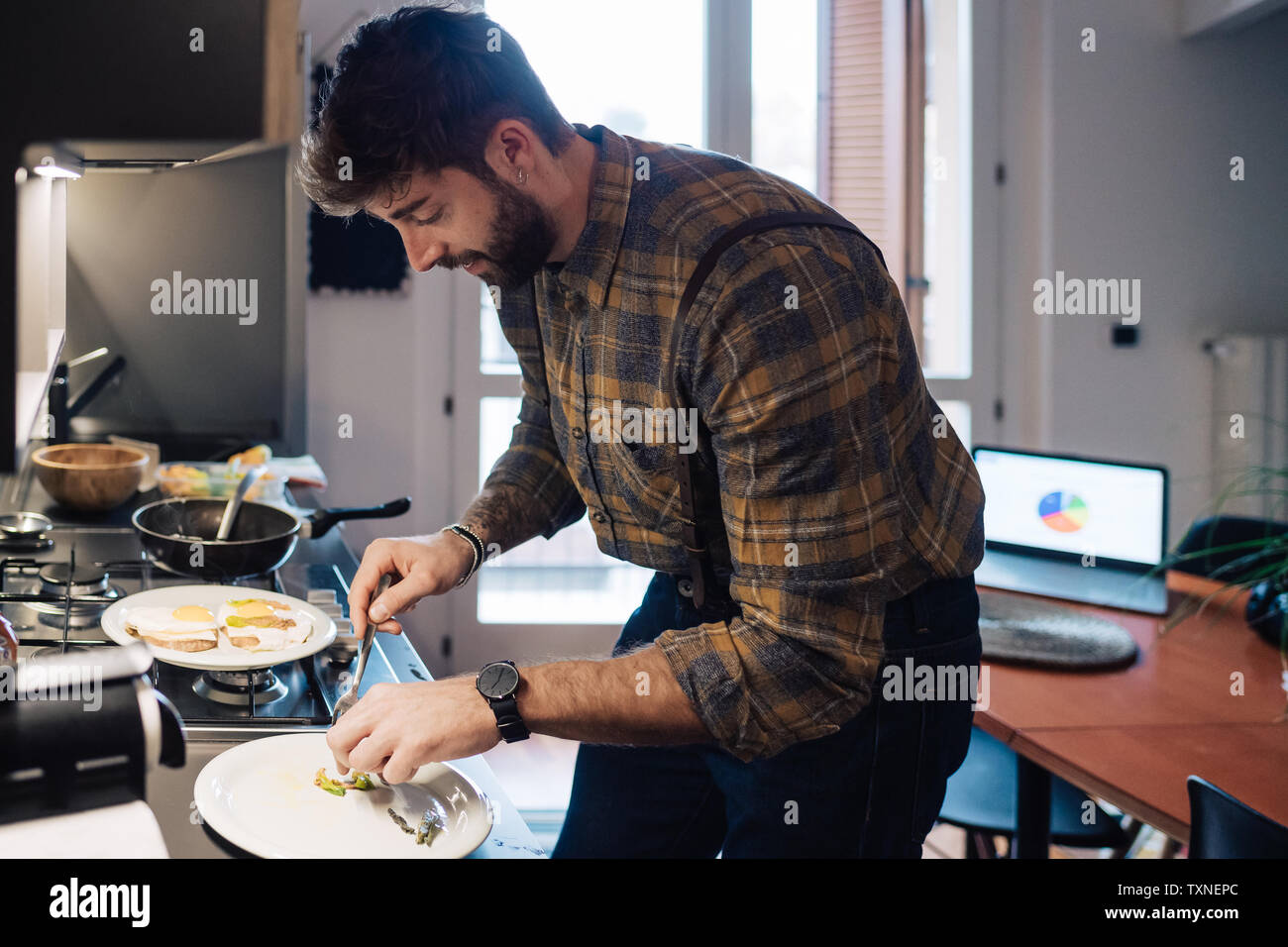 Mid adult man plating food at kitchen counter Stock Photo