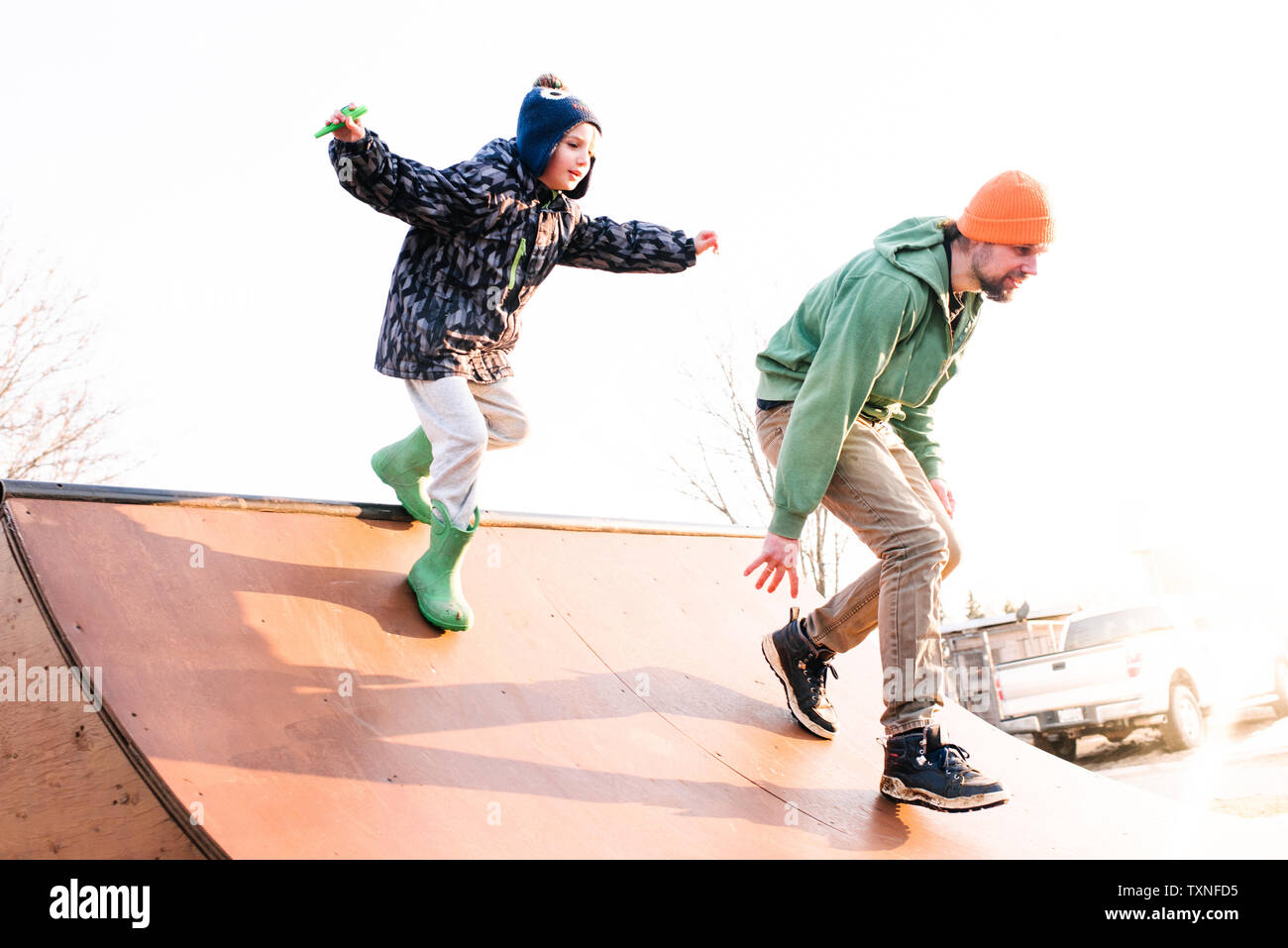 Boy chasing father on skateboard ramp, low angle view Stock Photo