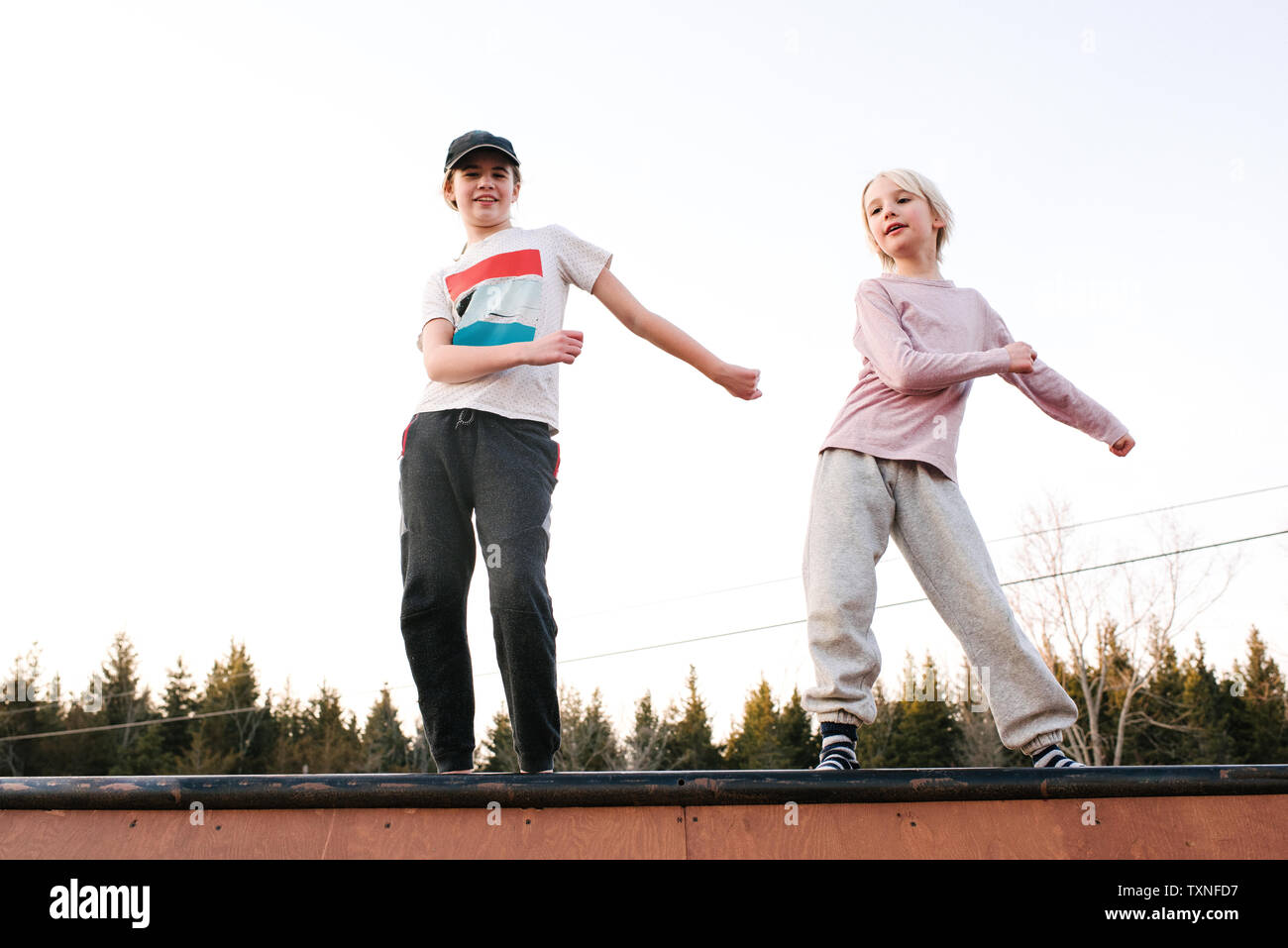 Boy and sister dancing on top of rural wooden structure Stock Photo