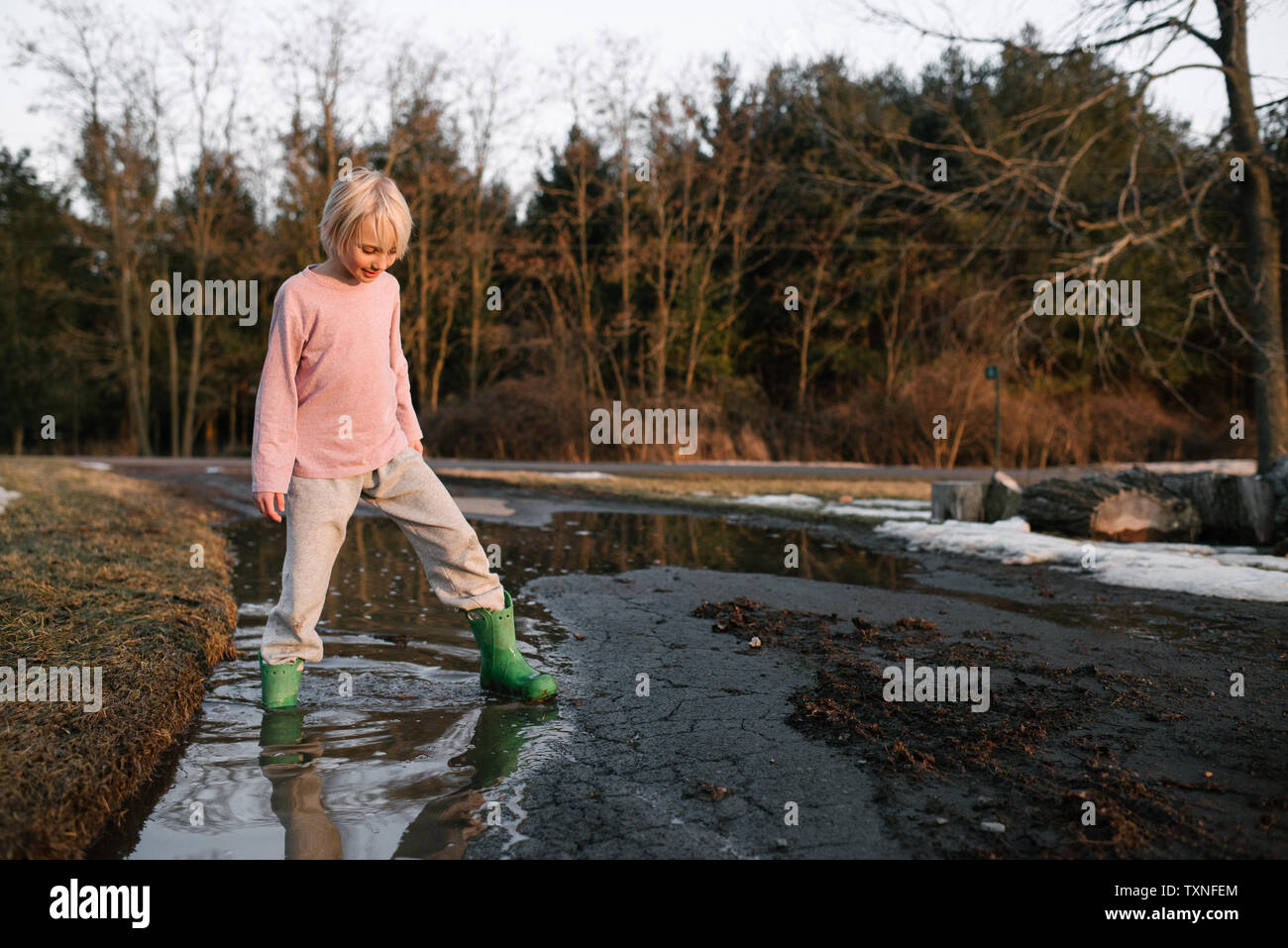 Boy stepping ankle deep in rural meltwater puddle Stock Photo