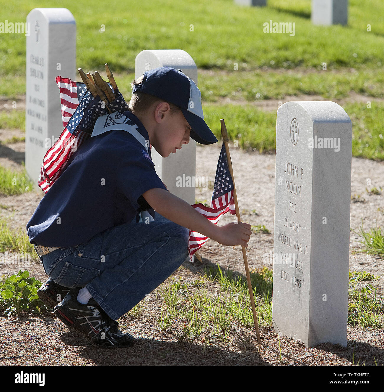 Scout Hunter Hall, 10, places an American flag in front of a gravesite in preparation for Memorial Day at Fort Logan National Cemetery in Denver on May 28, 2011.   Memorial Day celebrated on May 30th honors all those armed services men and women who died in military service to the United States.        UPI/Gary C. Caskey Stock Photo