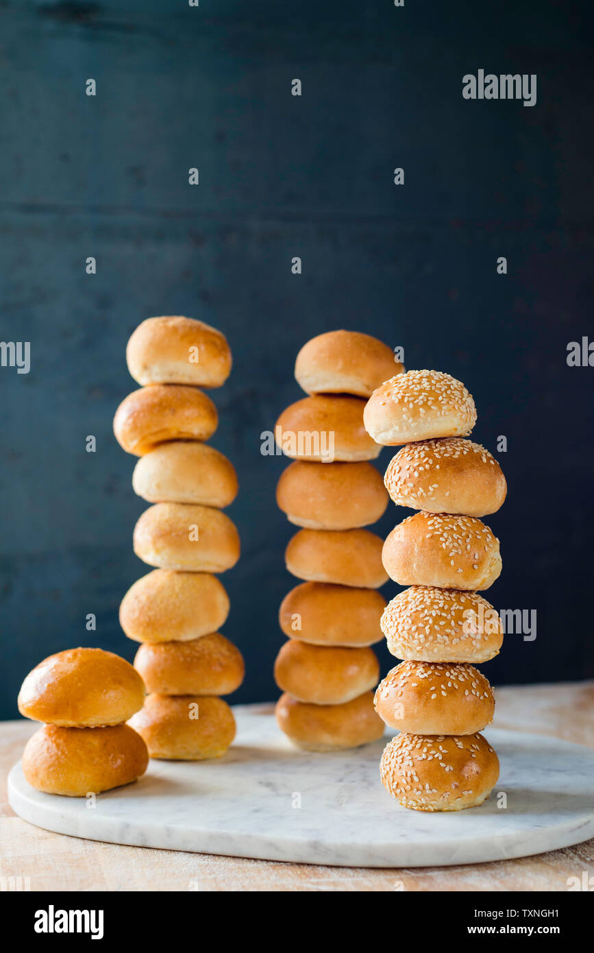 Large group of stacked white bread rolls on cutting board Stock Photo