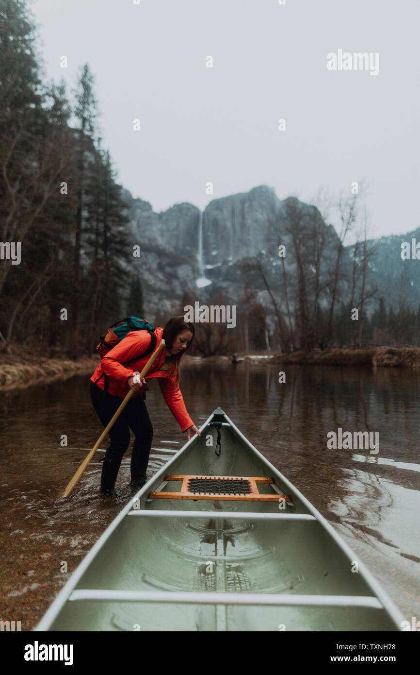 Young female canoeist pulling canoe in river, Yosemite Village