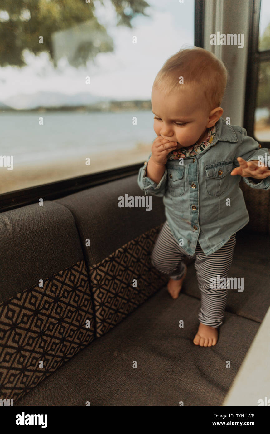 Baby walking on sofa in motorhome, Wanaka, Taranaki, New Zealand Stock Photo