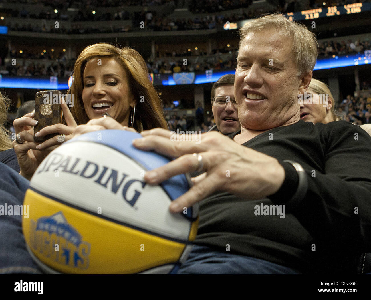 Denver Broncos Hall of Fame quarterback and current executive vice-president John Elway signs a Denver Nuggets autograph ball for the team mascot, Rocky, at the Pepsi Center on December 26, 2012 in Denver.  The Nuggets stopped the Lakers winning streak with a 126-114 victory.    UPI/Gary C. Caskey Stock Photo