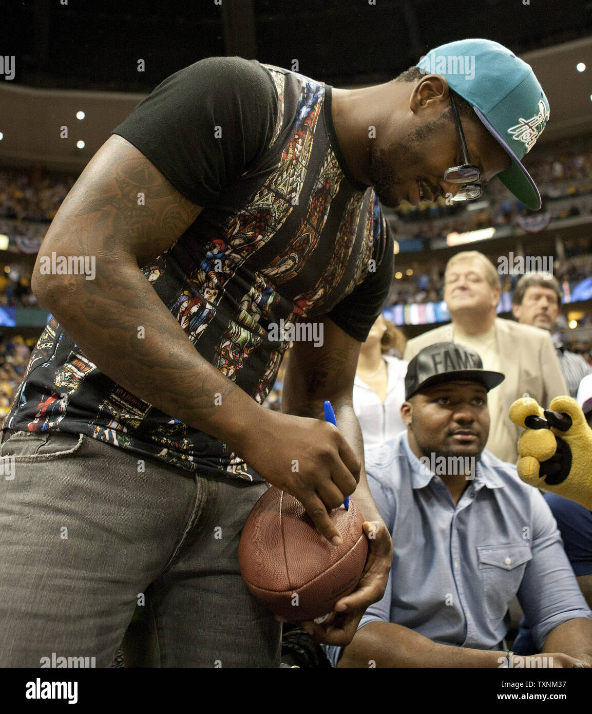 Denver Broncos star player Von Miller signs a football for Denver Nuggets mascot Rocky and his charity in the fourth quarter against the Golden State Warriors during the First Round Playoffs Game One in Denver on April 20, 2013.  The Nuggets take a 1-0 series lead defeating the Warriors 97-95.     UPI/Gary C. Caskey Stock Photo
