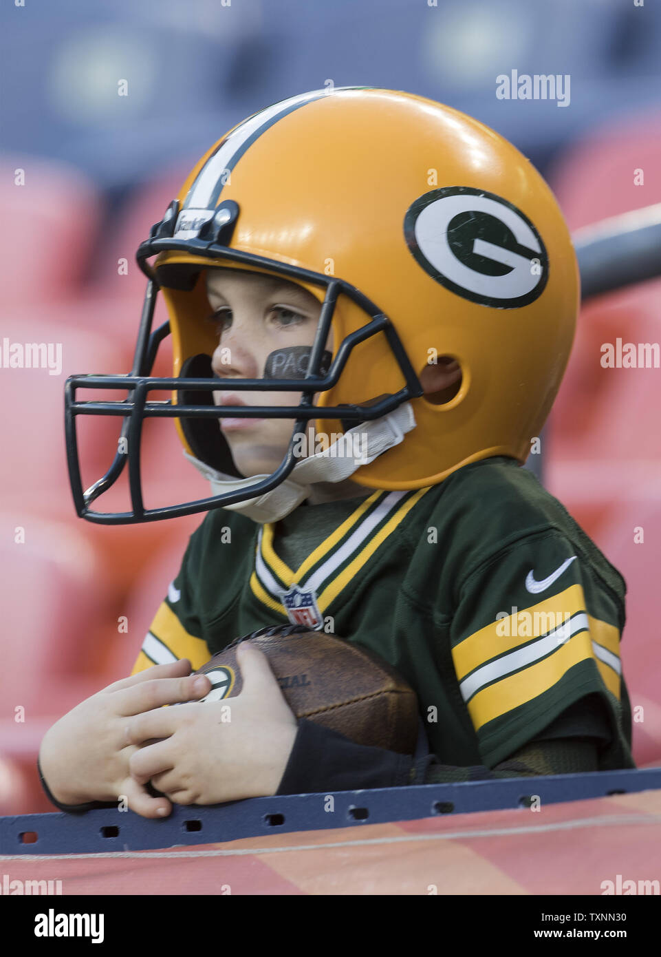 A very young Green Bay Packers fan wears his helmet at his first row seat watching warm ups at Sports Authority Field at Mile High in Denver on November 1, 2015. Photo