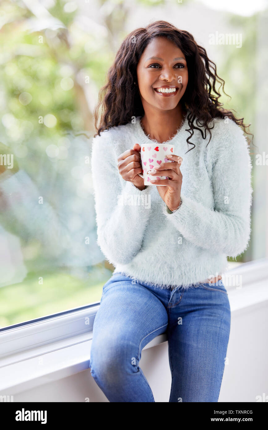 Ethnic girl relaxing with warm drink Stock Photo
