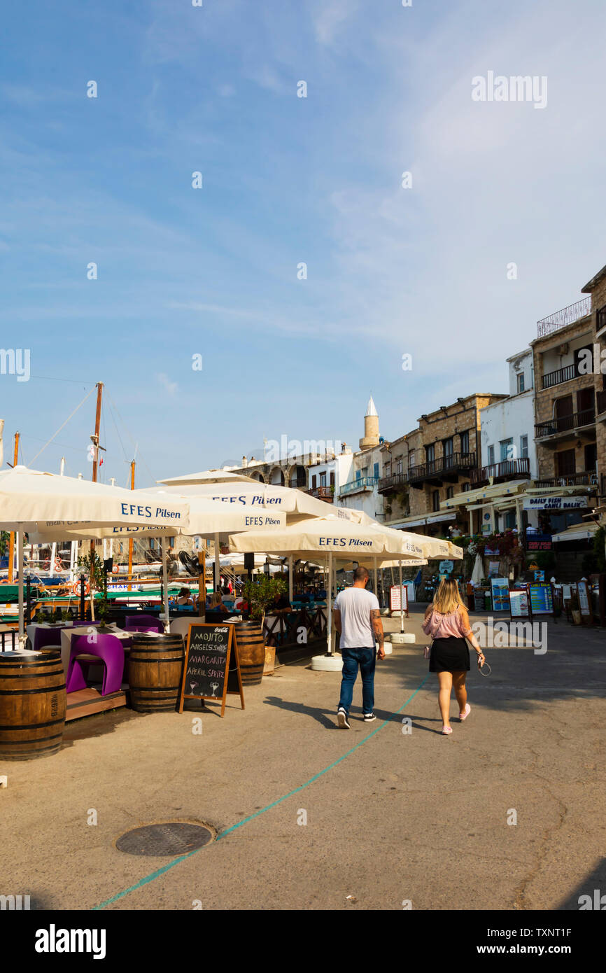 Tourists stroll along the harbour front restaurants, Kyrenia, Girne, Turkish Republic of Northern Cyprus. Stock Photo