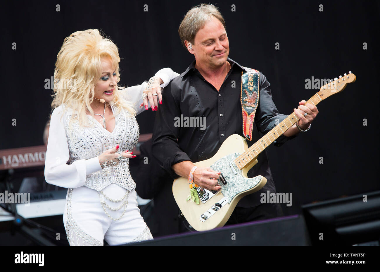 American country star Dolly Parton performing with her band leader Kent Wells on the main Pyramid Stage of Glastonbury Festival in 2014. Glastonbury Festival of Contemporary Performing Arts is the largest music festival in UK, attracting over 135,000 people each to Pilton, Somerset. Stock Photo
