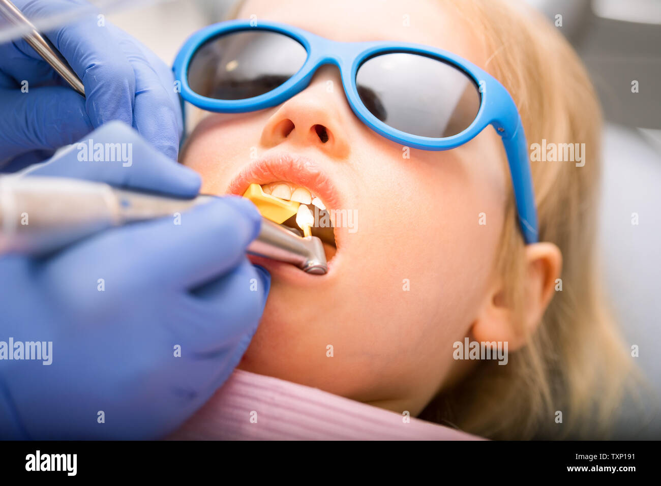 Dentist performing dental procedure to a little girl in pediatric
