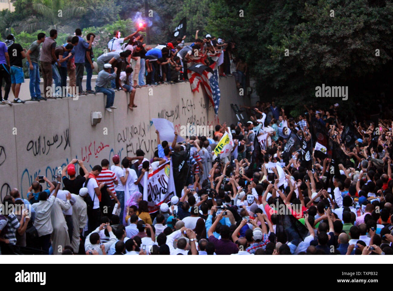 Egyptian protesters tear down an American flag at the United States embassy in Cairo on September 11, 2012, during a demonstration against a film deemed offensive to Islam and the Prophet Mohammad.  In Libya, Islamic extremists killed the American ambassador as they stormed the American consulate in Benghazi in anger against the little known film by an amateur American filmmaker.  UPI/Ahmed Jomaa Stock Photo