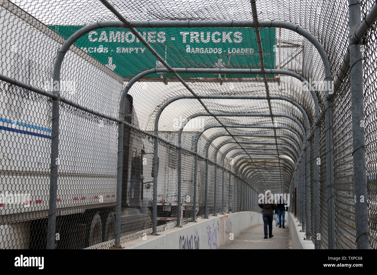 Pedestrians walk alongside large trucks on the Bridge of the Americas