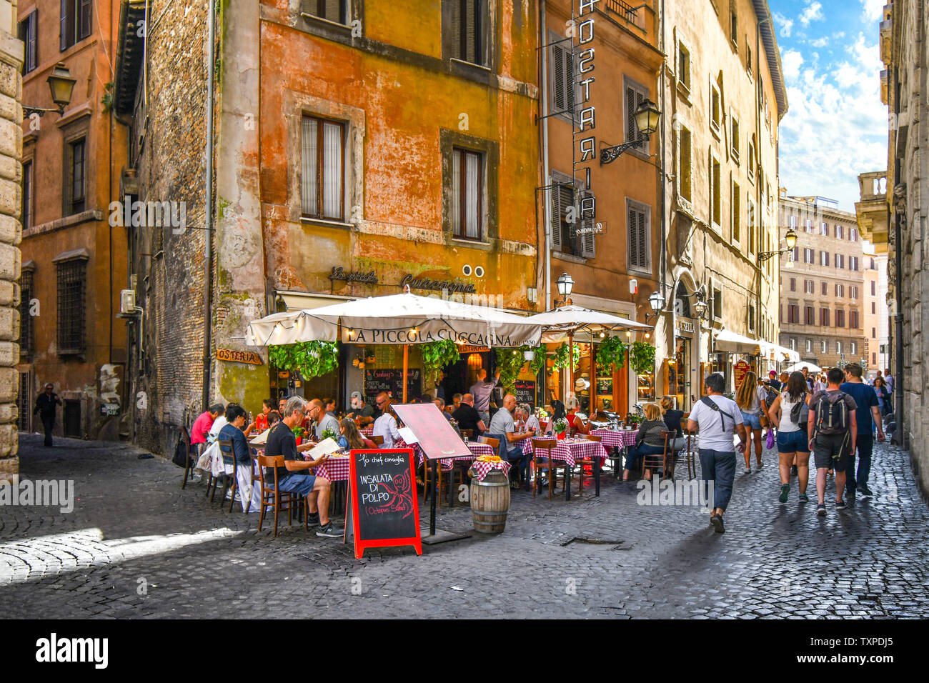 Tourists enjoy lunch on a summer day at an Italian sidewalk cafe restaurant in an alley near the historic center of Rome, Italy. Stock Photo