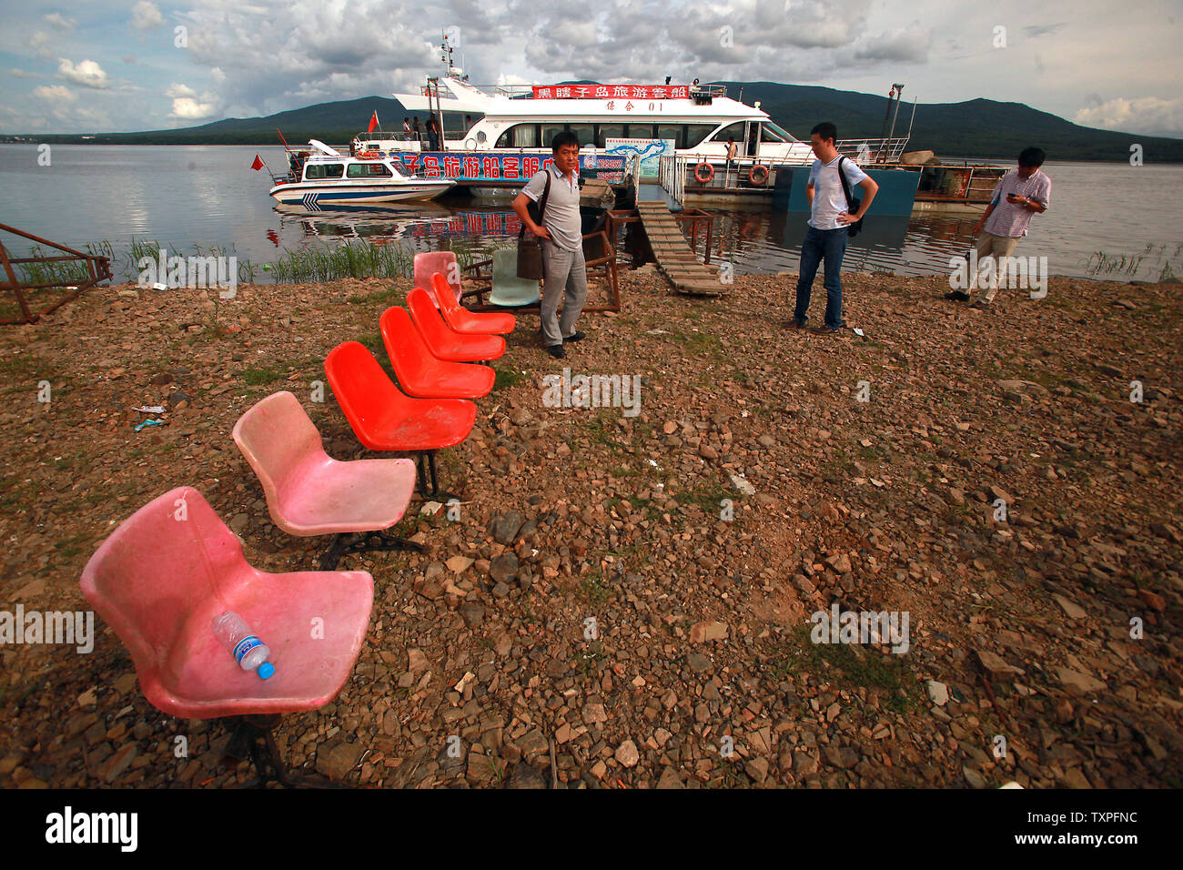 A Chinese tourist boat waits for passengers before heading up the Songhua River and its wetlands, which serves as a natural border between China and Russia (background), in Fuyuan, a frontier town in China's northern Heilongjiang Province on August 4, 2013.  Ecotourism has been part of household vocabularies in China for a decade, however experts believe that the concept still has a long way to go in China.  Most domestic tourists are more interested in sightseeing than promoting environmental programs and awareness, according to a study.     UPI/Stephen Shaver Stock Photo