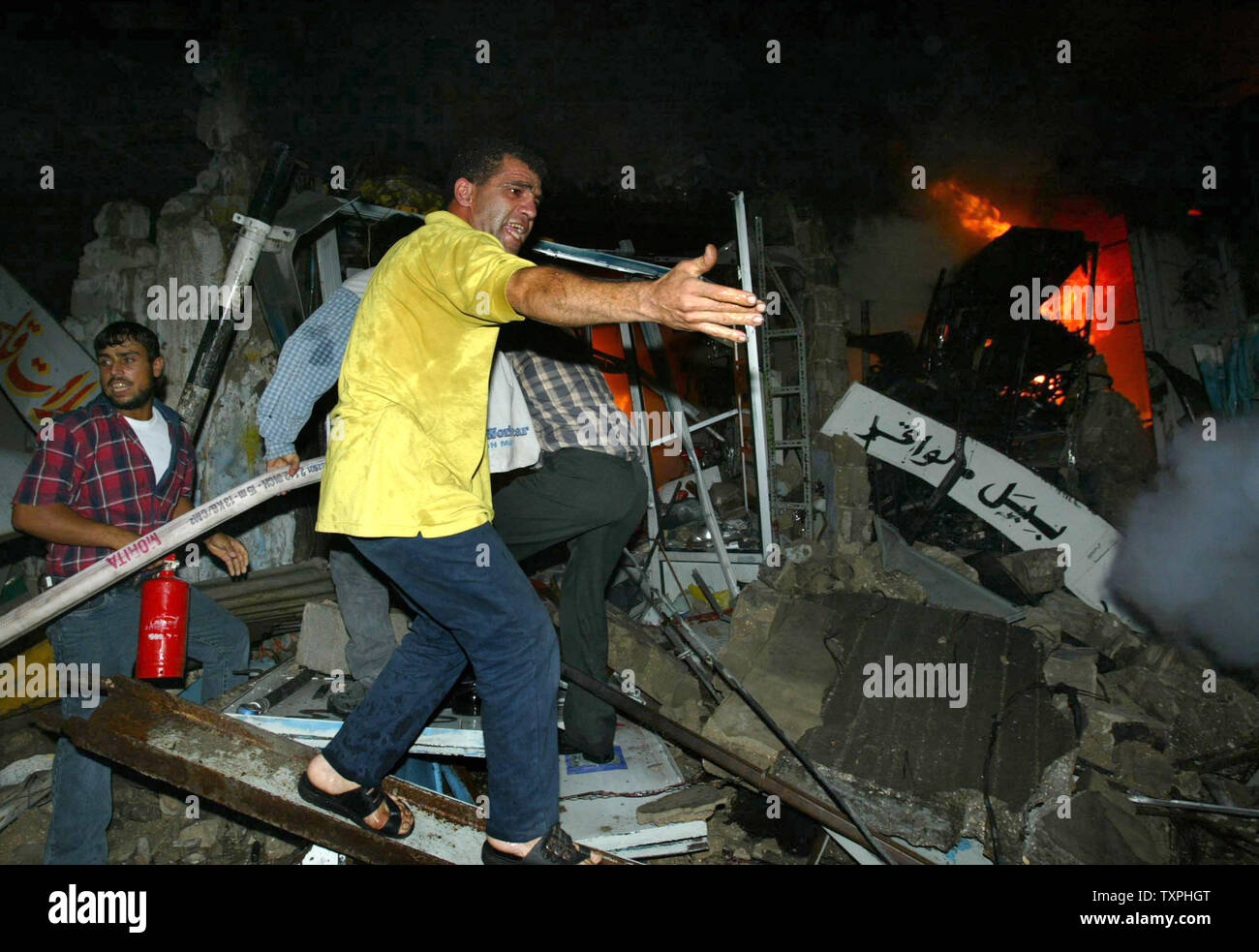 Palestinians help fire rescue workers after an Israeli missile hit a Palestinian car in the al Shejaeiya area of Gaza City on October 2, 2004.  An Israeli airstrike killed Mehdi Mushtaha and Khaled Amreet, both members of Hamas' military wing, as they travelled in a car in Gaza City, sources said. Four bystanders were also wounded in the attack.  (UPI Photo/ STR) Stock Photo