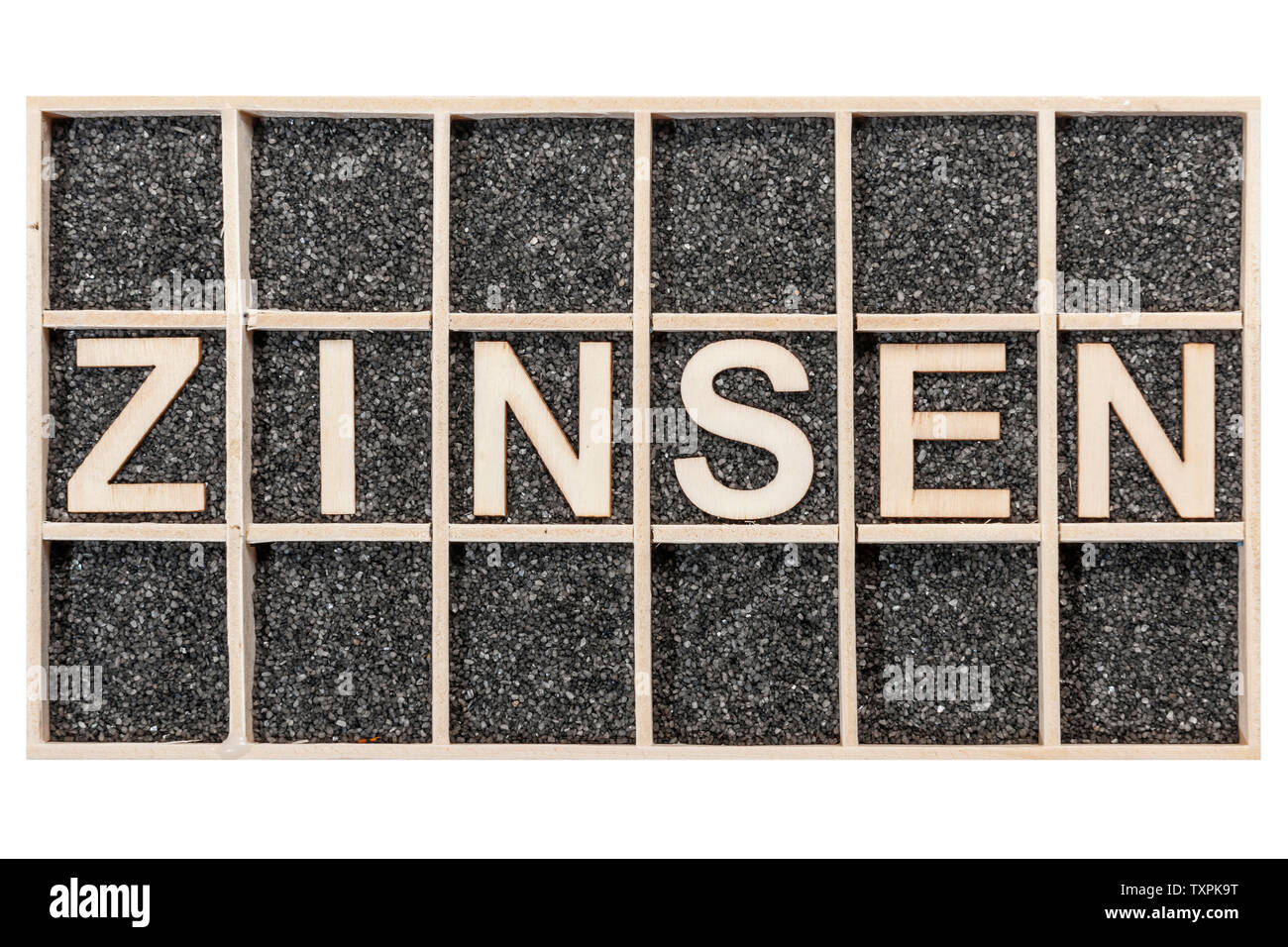 Plywood letters arranged in a collecting box with black decorative sand representing the word ZINSEN in top view isolated on white. Stock Photo