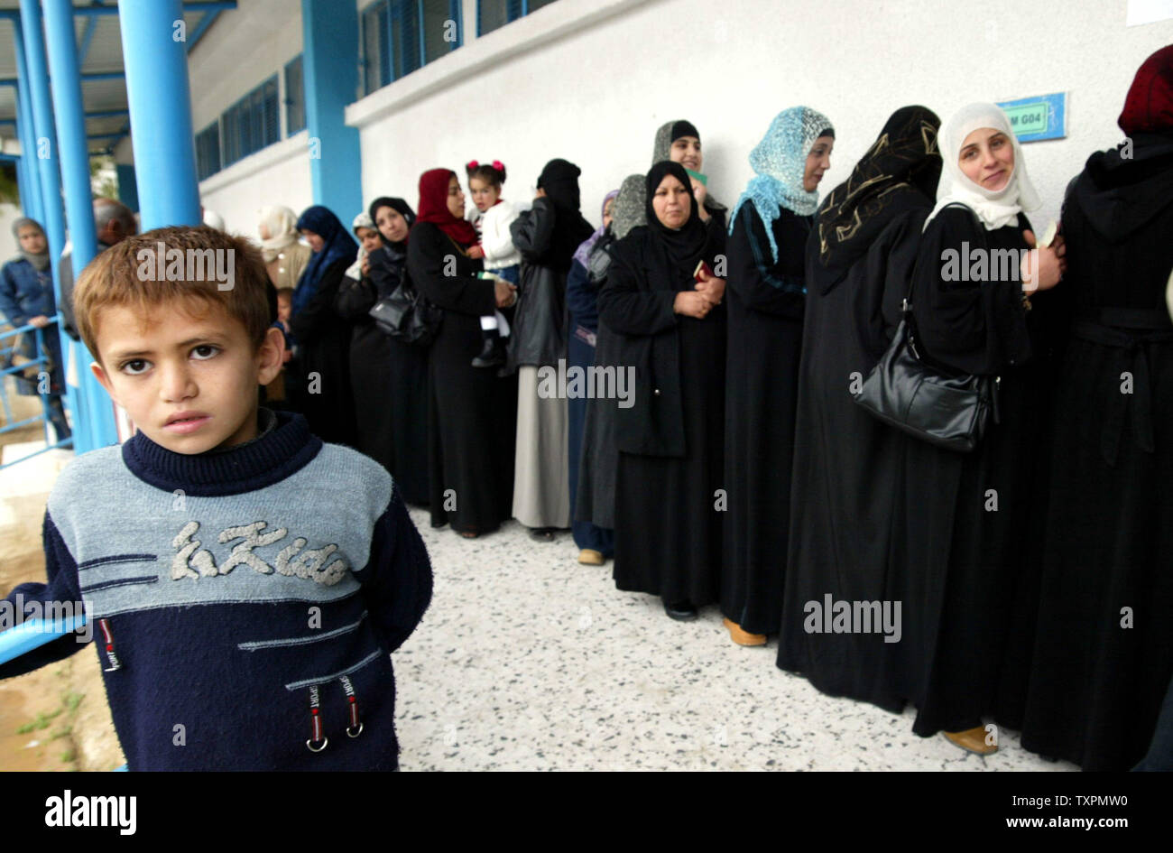 A Palestinian child stands beside women waiting in line to cast their ballots inside a polling station in Gaza City January 25, 2006. Polls opened in the West Bank and Gaza Strip in the only second ever election to the Gaza-based parliament since the formation of the Palestinian Authority. The poll will see the ruling Fatah faction face the first major test to its hold on power from the radical Islamist movement Hamas.    (UPI Photo/Ismael Mohamad) Stock Photo