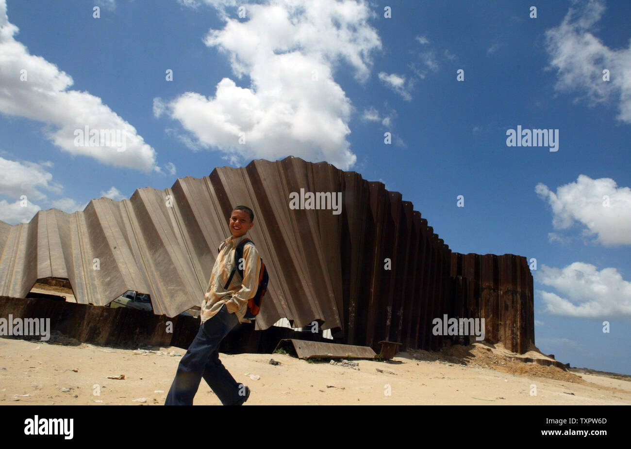 A Palestinian boy crosses the breached border fence between the Gaza ...