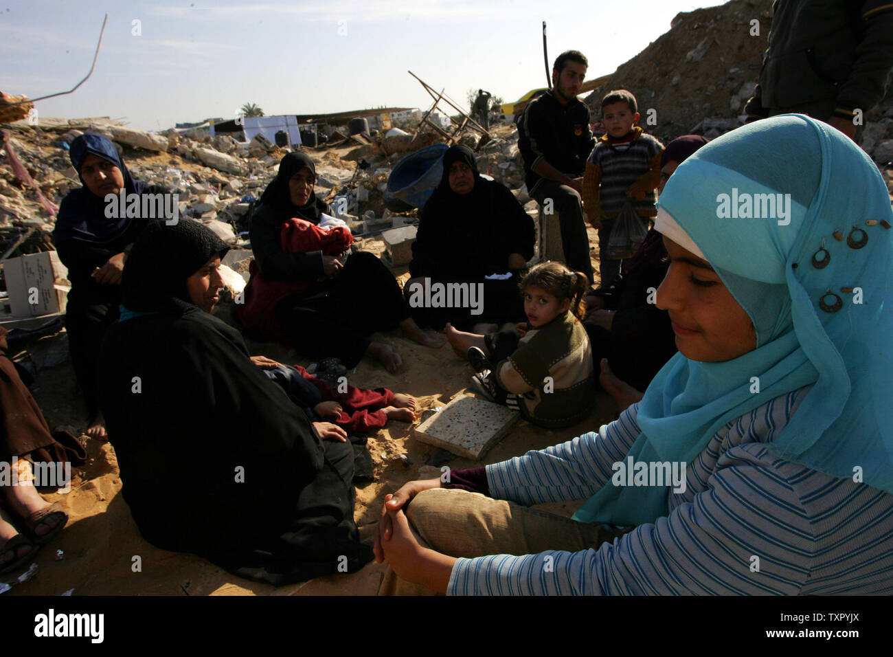 A Palestinian family sits on the rubble of their home, destroyed during ...