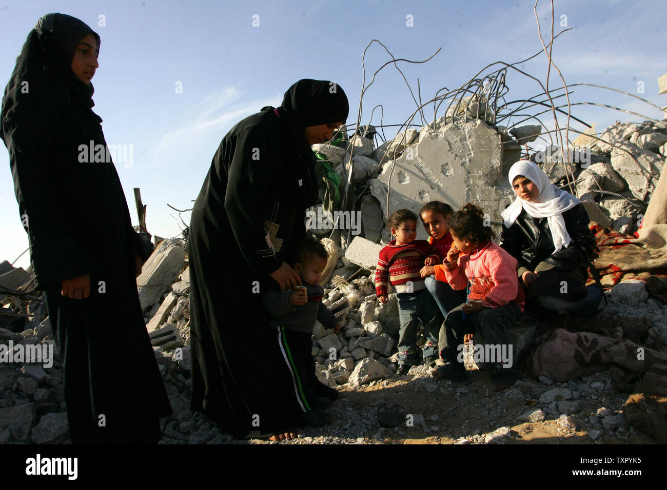 A Palestinian family sits on the rubble of their home, destroyed during ...