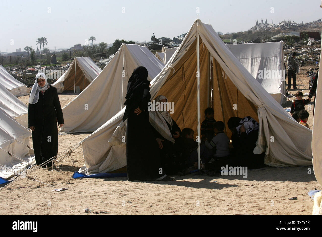 A Palestinian family sits at the entrance of a tent serving as ...