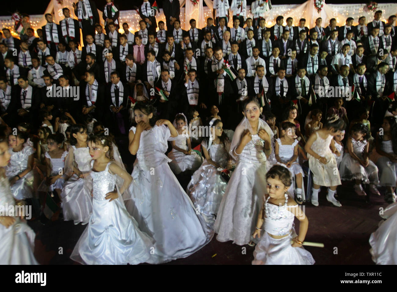 Palestinian girls, dressed as bridesmaids, during a mass wedding in Jabalya in the northern Gaza Strip July 30, 2009. Some 450 couples were married in Jabalya in a group wedding organized by the Islamic Society, a group affiliated to Hamas. The newly wedded brides held a separate closed-door celebration for their weddings.(UPI photo /Ismael Mohamad) Stock Photo