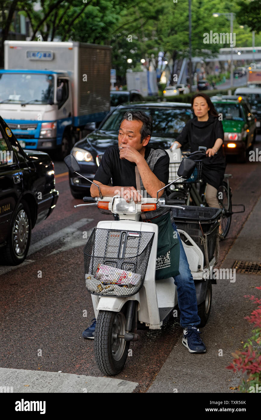TOKYO, JAPAN, May 10, 2019 : Man waiting in the traffic on a bike, smoking a cigarette. Stock Photo