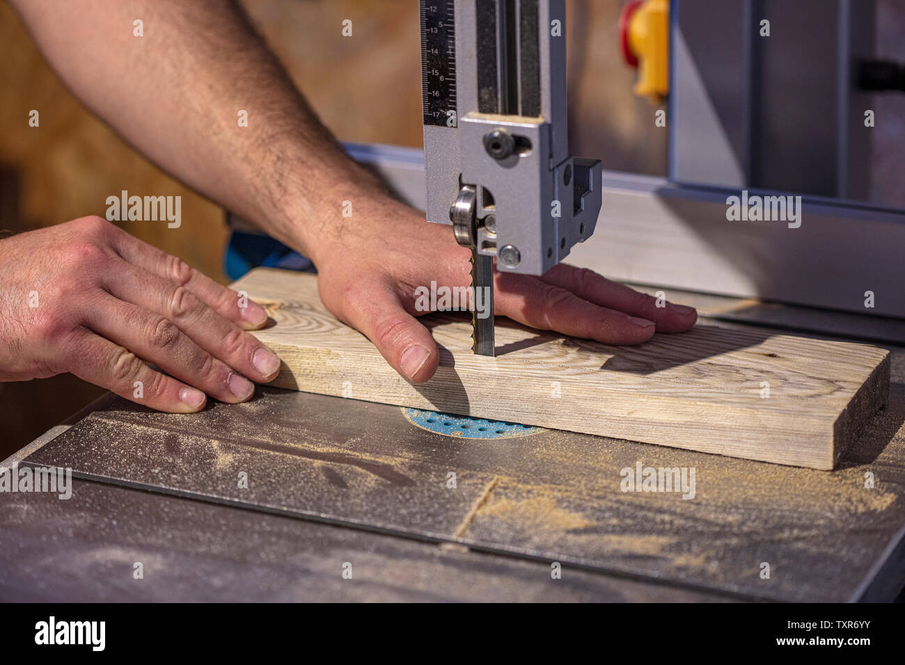 detail of a carpenter's hand next to a band saw blade. concept of safety at work and accidents Stock Photo