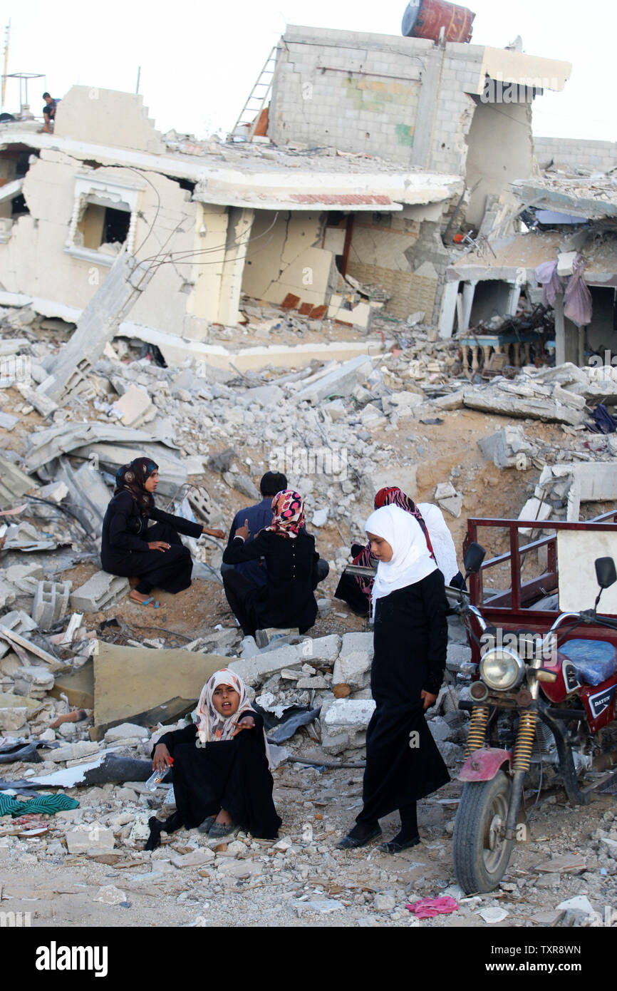 Palestinian women sit  on the rubble of their home which was destroyed during the Israeli army summer's military offensive on the Gaza Strip, on October 1, 2014, in Khan Yunis' Khuzaa neighbourhood in the southern Gaza Strip. Israeli Prime Minister Benjamin Netanyahu has complained to UN chief Ban Ki-moon that a probe by the world body into the Gaza war is one-sided, his foreign ministry said. UPI/Ismael Mohamad Stock Photo