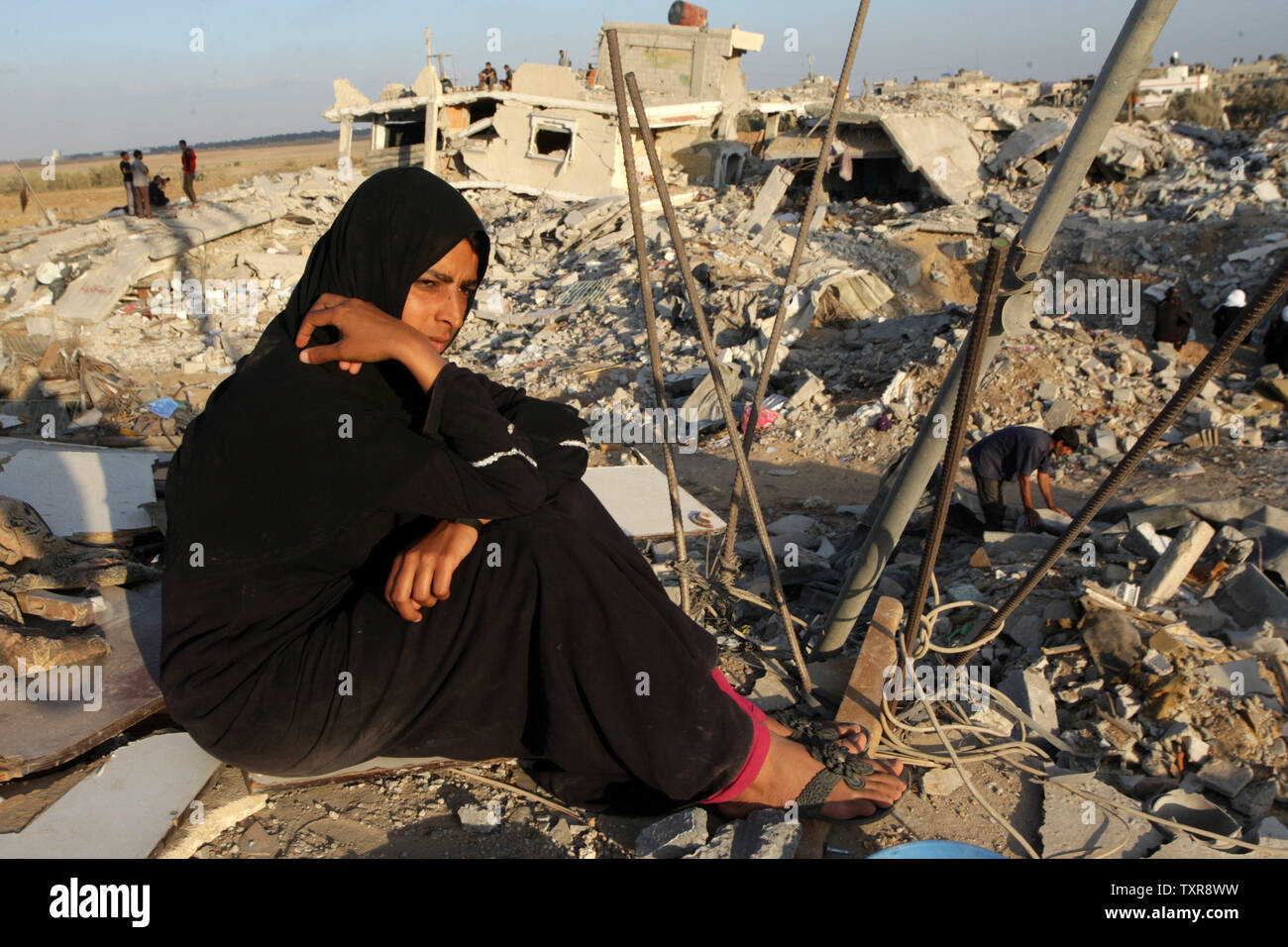 A palestinian woman sit  on the rubble of her home which was destroyed during the Israeli army summer's military offensive on the Gaza Strip, on October 1, 2014, in Khan Yunis' Khuzaa neighbourhood in the southern Gaza Strip. Israeli Prime Minister Benjamin Netanyahu has complained to UN chief Ban Ki-moon that a probe by the world body into the Gaza war is one-sided, his foreign ministry said. UPI/Ismael Mohamad Stock Photo