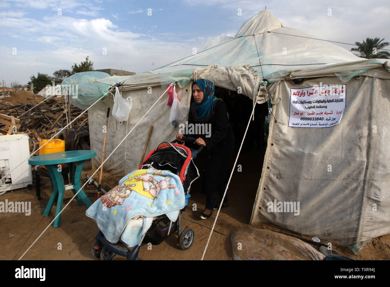 A Palestinian woman stand with her child in front of a tent serving as ...