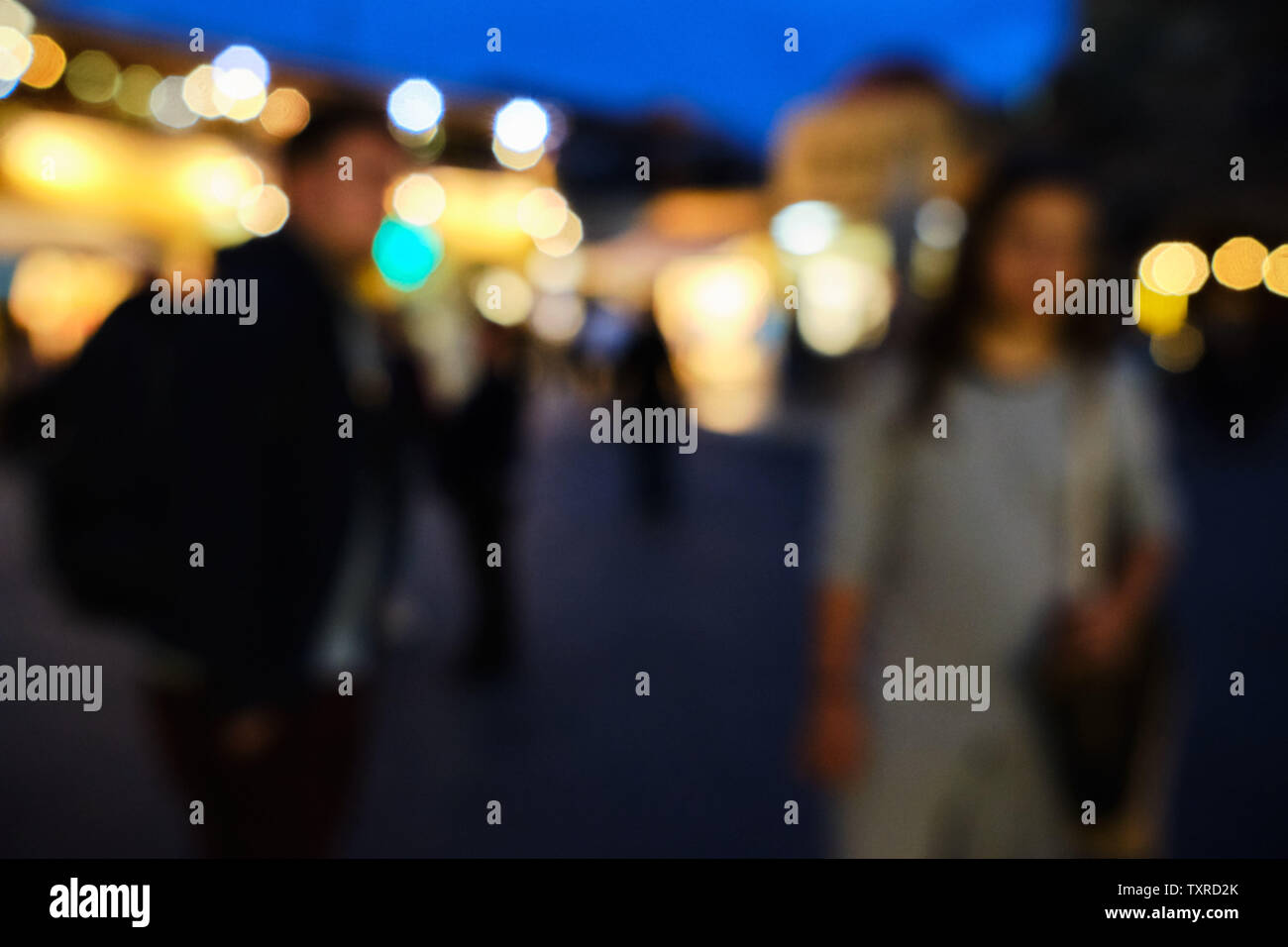 The whole picture is out of focus with two individuals in the foreground and street lights in the background Stock Photo
