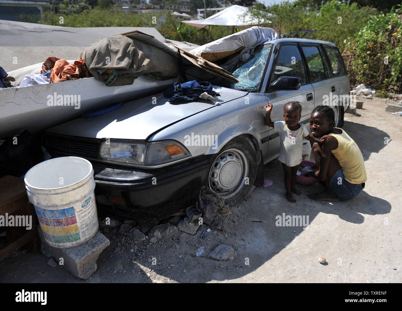 A Woman And Child Wash Clothing Under A Smashed Car In Port Au