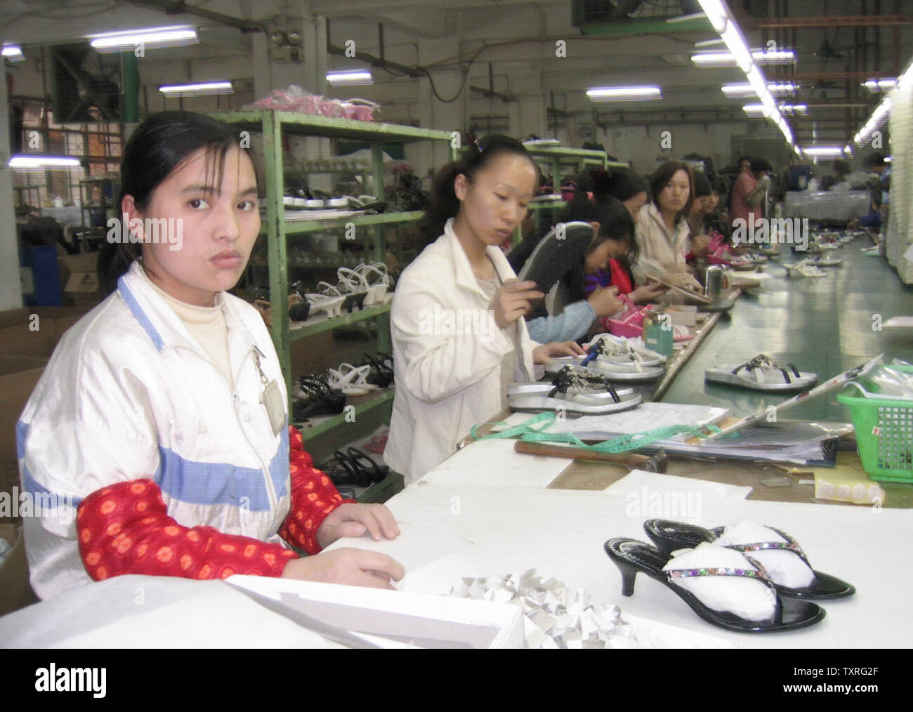 Most Chinese factory workers are young men and women from rural areas, like these at the Tat Fat Shoe Factory in Dongguan, China, recently.  The workers in the factory are from various parts of China with different dialects, but here they speak Mandarin to communicate with each other.  One common goal has brought them together far from their families -- the piecework they do every day provides them a livelihood to send money back home. For possible use with globalfaces-china-factory moved on April 29, 2004. (UPI Photo/Yan Tai) Stock Photo