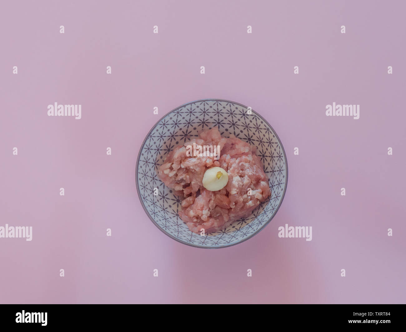 Minced pork meat in a bowl on pink background Stock Photo