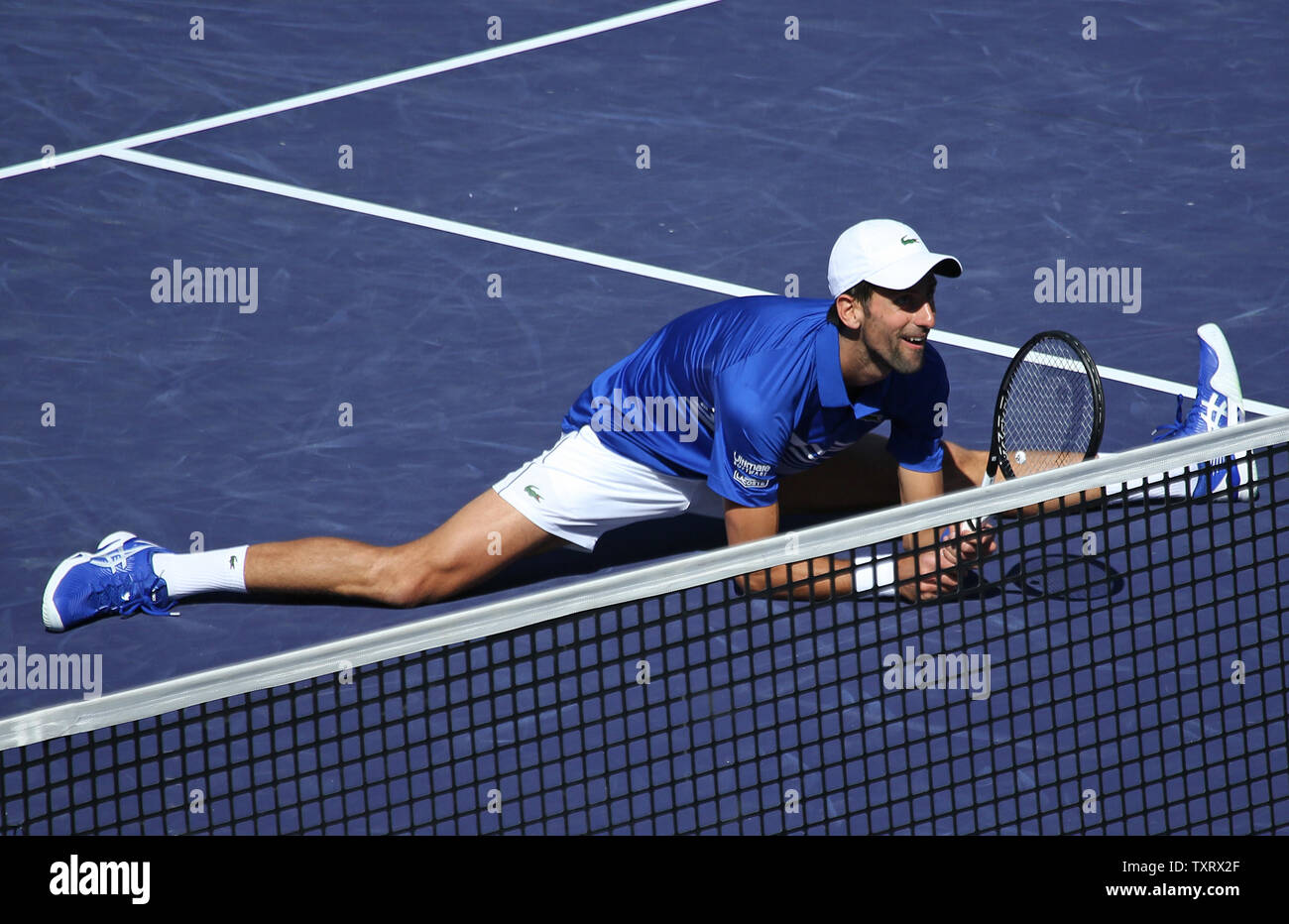 Novak Djokovic of Serbia does the splits during an exhibition match at the  BNP Paribas Open in Indian Wells, California on March 16, 2019. The  exhibition was arranged after the cancellation of
