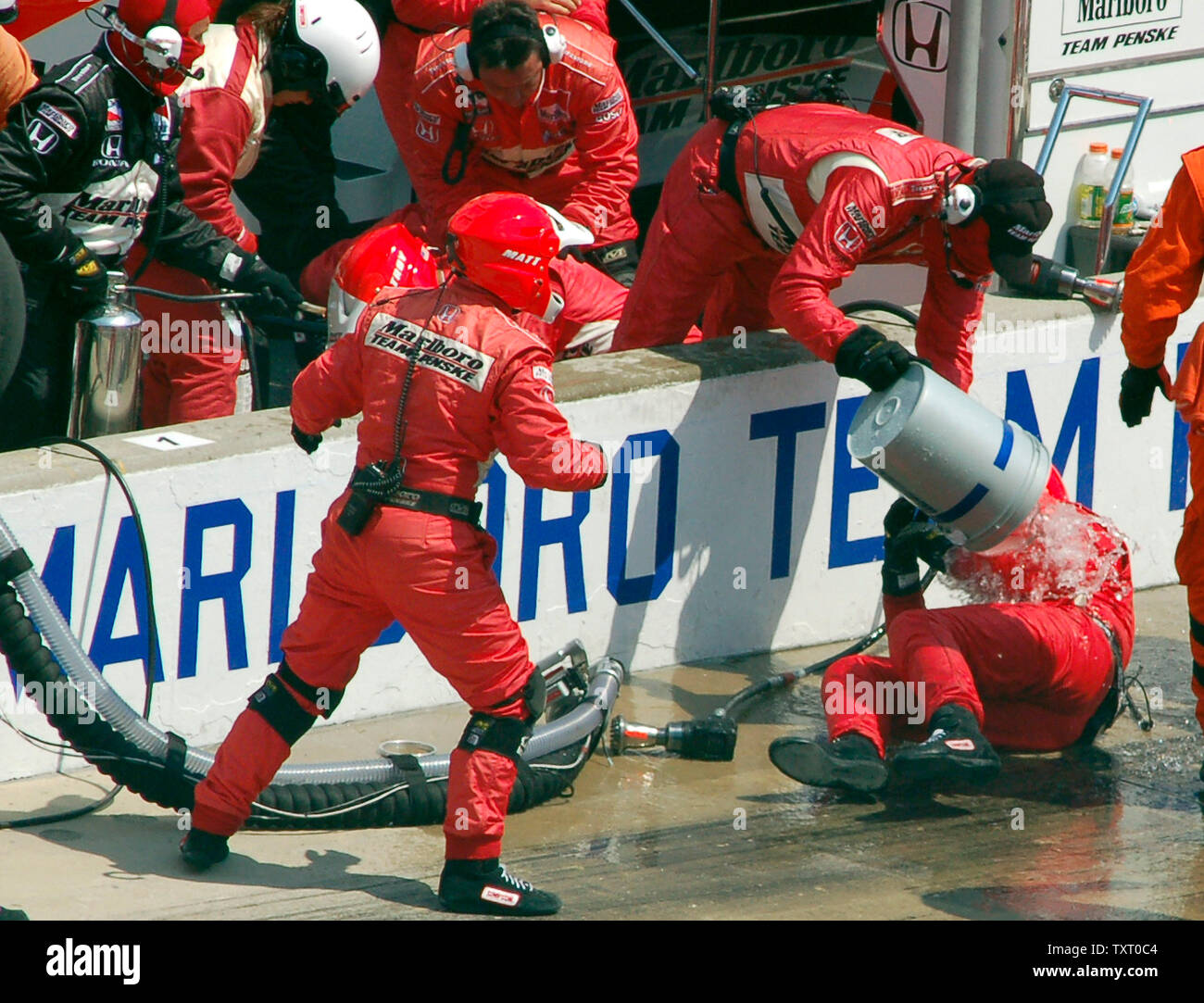 Marlboro Team Penske members run to douse the fuel filler for driver Sam Hornish Jr. with water during a pit stop in the 90th running of the Indianapolis 500 May 28, 2006 in Indianapolis, In. Hornish Jr. ripped loose the fuel line as he tried to leave his pit box dousing his crewman with fuel. Sam Hornish of Marlboro Team Penske won the race with the second closest finish. (UPI Photo/Paula Ritchey) Stock Photo