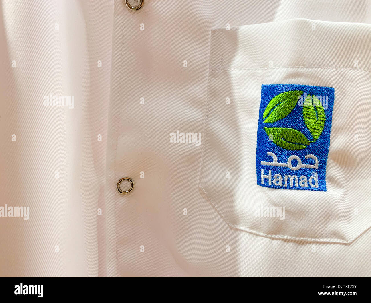 White workwear of a doctor or assistant with Hamad logo in Arabic and English. Hamad (HMC) is the biggest medical provider. April 2019, Doha/ Qatar. Stock Photo