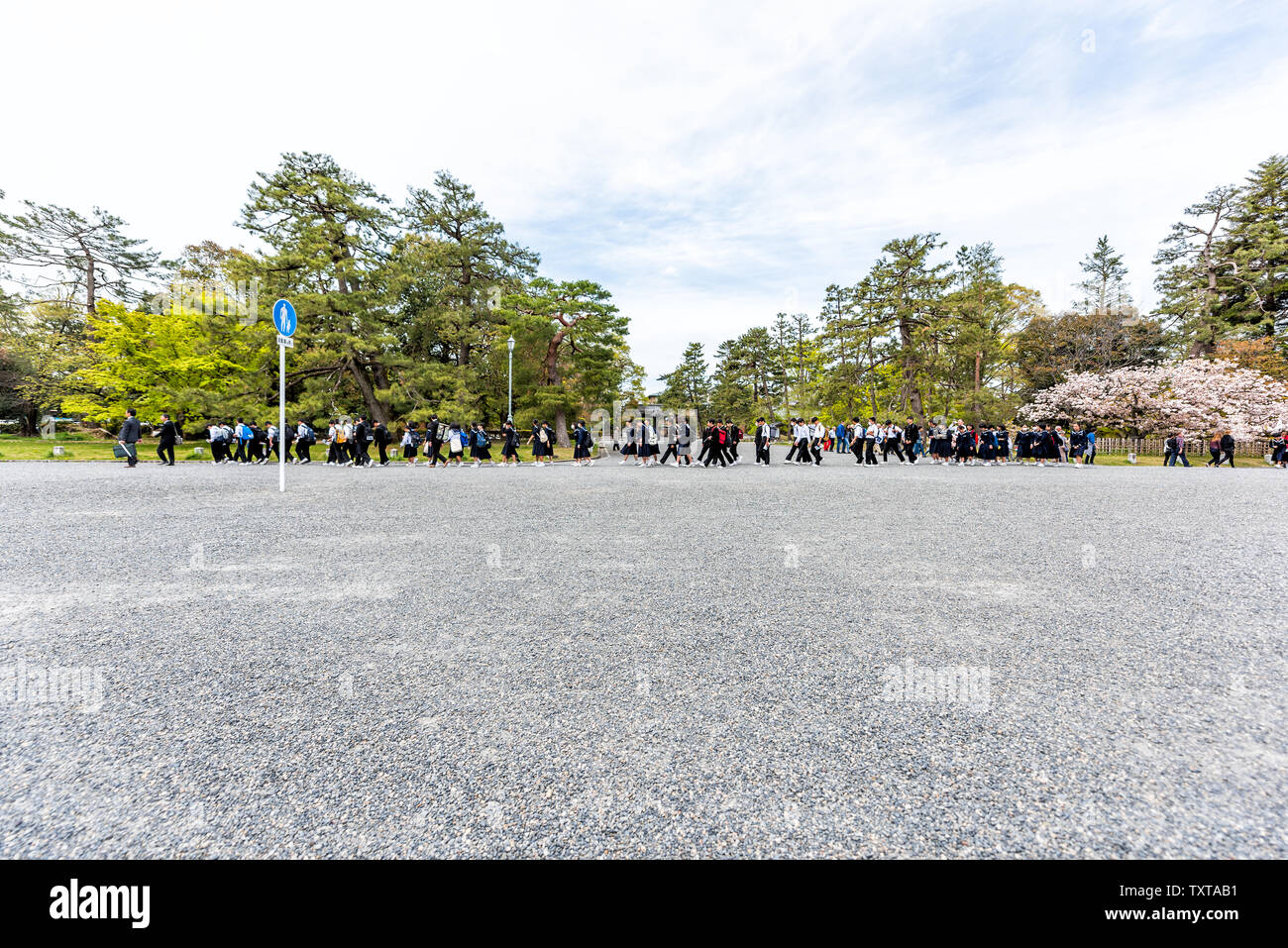 Kyoto, Japan - April 17, 2019: Road with many people school children boys and girls walking in line on gravel street near Imperial Palace on field tri Stock Photo