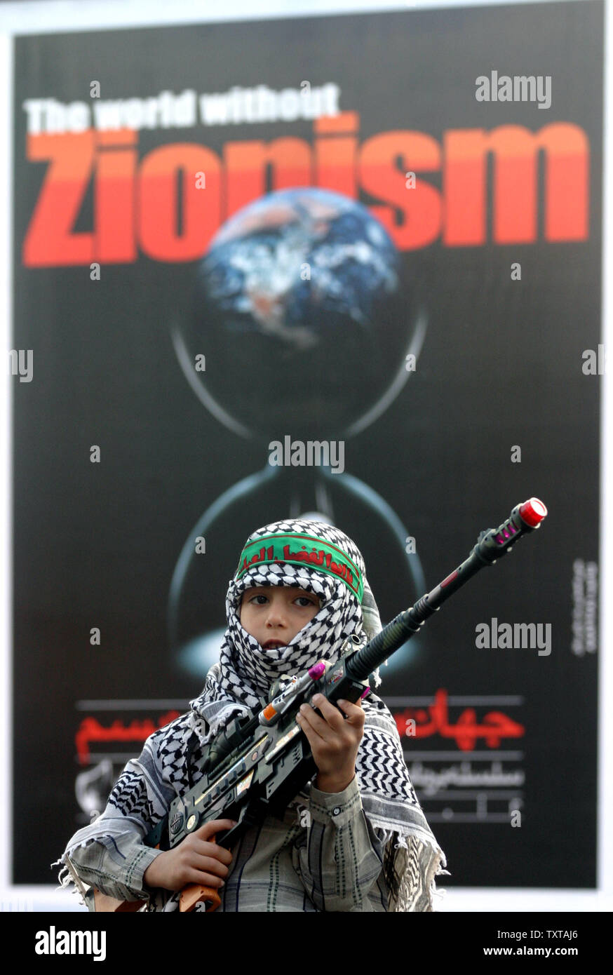 An Iranian boy holds a gun in front of an anti-zionism poster during an anti-Israel rally on Friday Oct. 28, 2005 in Tehran.  (UPI Photo/Mohammad Kheirkhah) Stock Photo