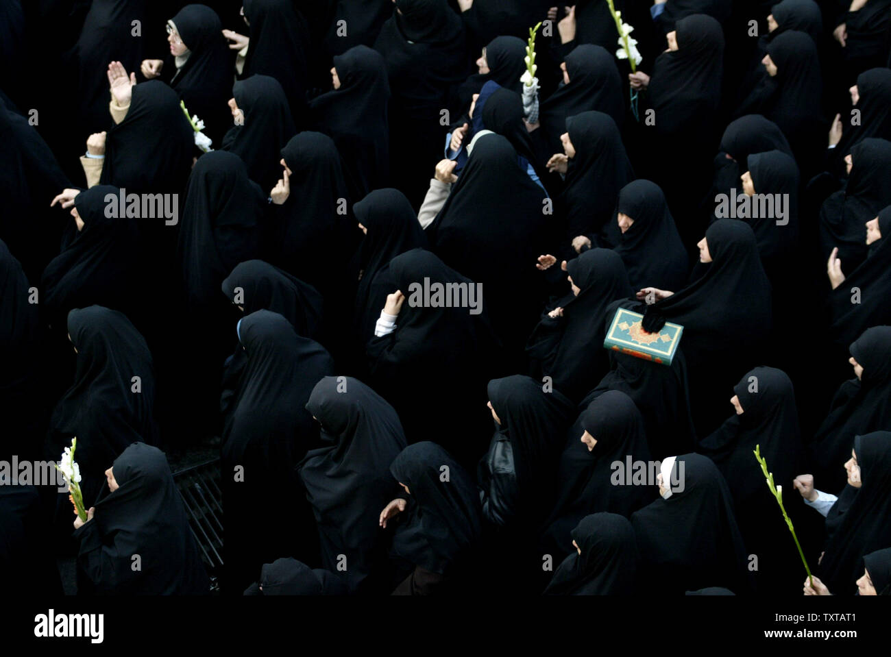 Iranian women, one holding a Koran, follow a truck carrying the dead during a funeral ceremony for 110 people that were killed during the 8-year Iran-Iraq war, whose bodies were finally recovered after 17 years, in Tehran, Iran, on November 25, 2005.   (UPI Photo/Mohammad Kheirkhah) Stock Photo