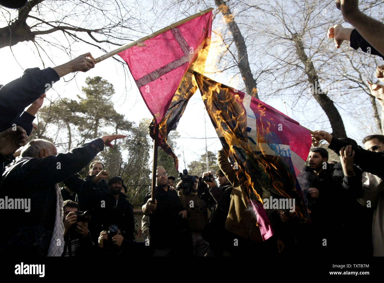 Members of Iran's hardline Islamist Basij militia burn a Denmark flags during demonstration in front of the Danish Embassy to support Iran's nuclear program and to protest a Danish newspaper cartoon that is being received as an insult to the Prophet Mohammed, in Tehran, Iran, February 10, 2006.  (UPI Photo/Mohammad Kheirkhah) Stock Photo