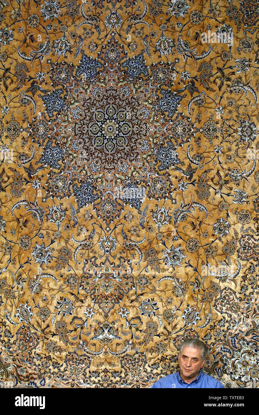 An Iranian carpet seller from Isfahan sits under a big carpet during