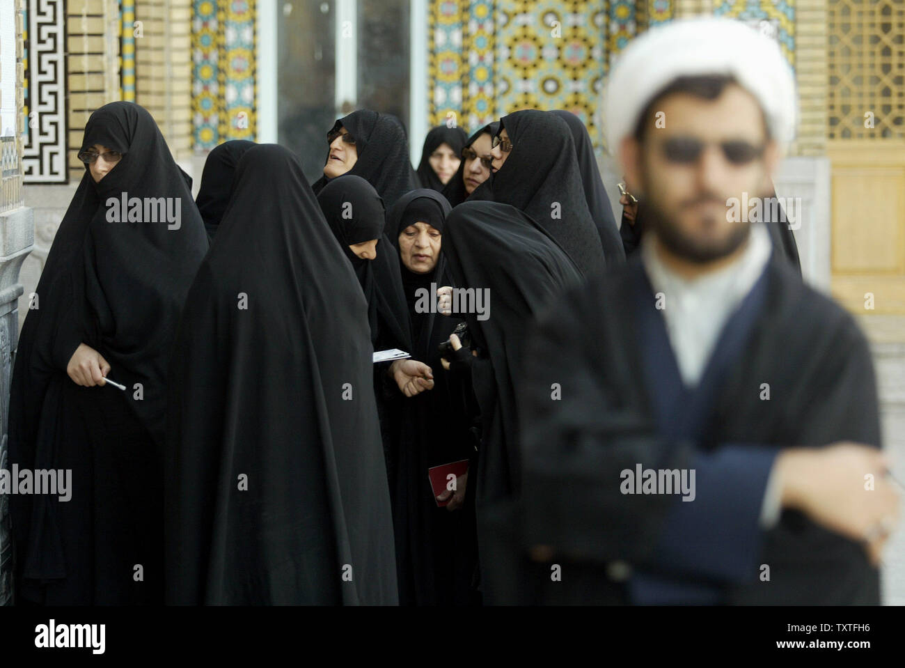 Iranian women hold their certificates as they stand in line next to a clergyman before casting their votes in Iran's parliamentary election, at a polling station at the Saint Masoumeh shrine in the holy city of Qom, 80 miles (130 kilometers) south of Tehran, Iran on March 14, 2008. (UPI Photo/Mohammad Kheirkhah) Stock Photo