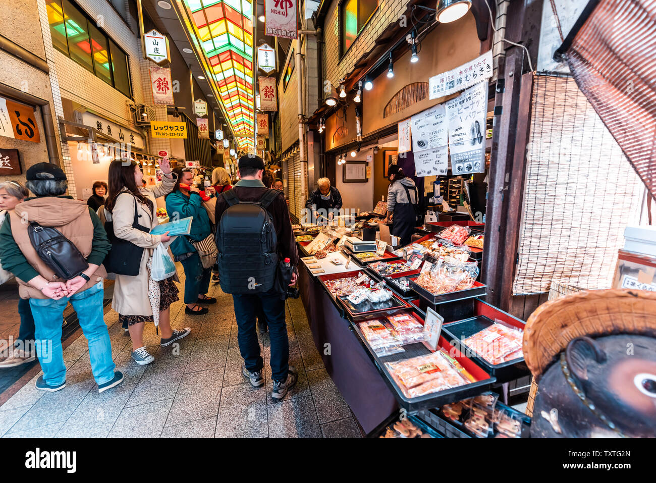 Kyoto, Japan - April 17, 2019: City street with people shopping in Nishiki market shops food vendor selling souvenirs rice crakers Stock Photo