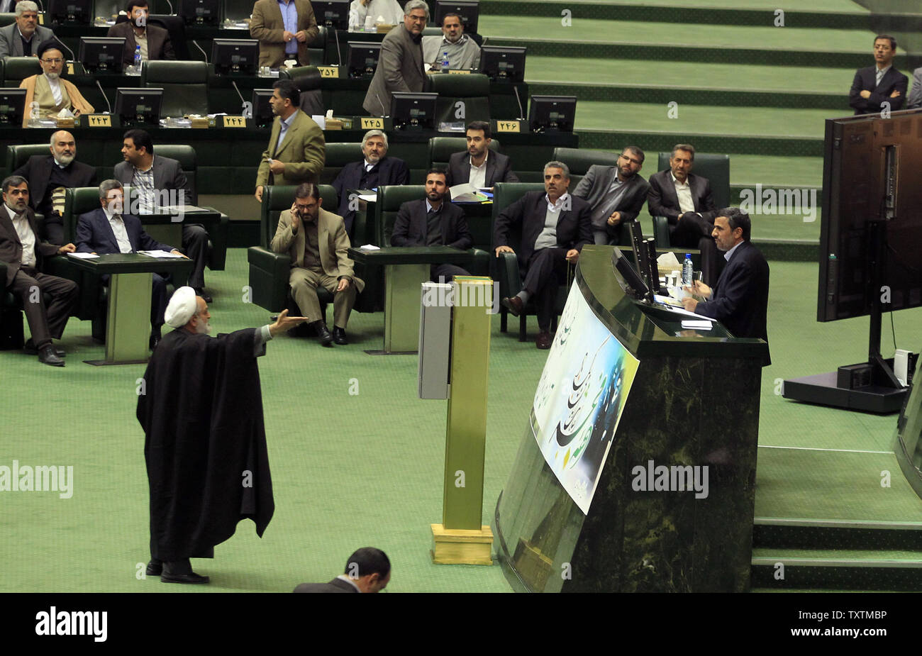 A member of Iranian parliament  protests while President Mahmoud Ahmadinejad (R) speaks during the impeachment of the labor minister , Abdolreza Sheikholeslami, unseen, at the parliament in Tehran, Iran on February 3, 2013. Out of 272 lawmakers in the parliament on Sunday, 192 voted against the labor minister. The main reason behind the MP's decision to dismiss the minister was Sheikholeslami's refusal  to remove former Tehran prosecutor general Saeed Mortazavi from his post as the director of the Social Security Organization.     UPI/Maryam Rahmanian Stock Photo