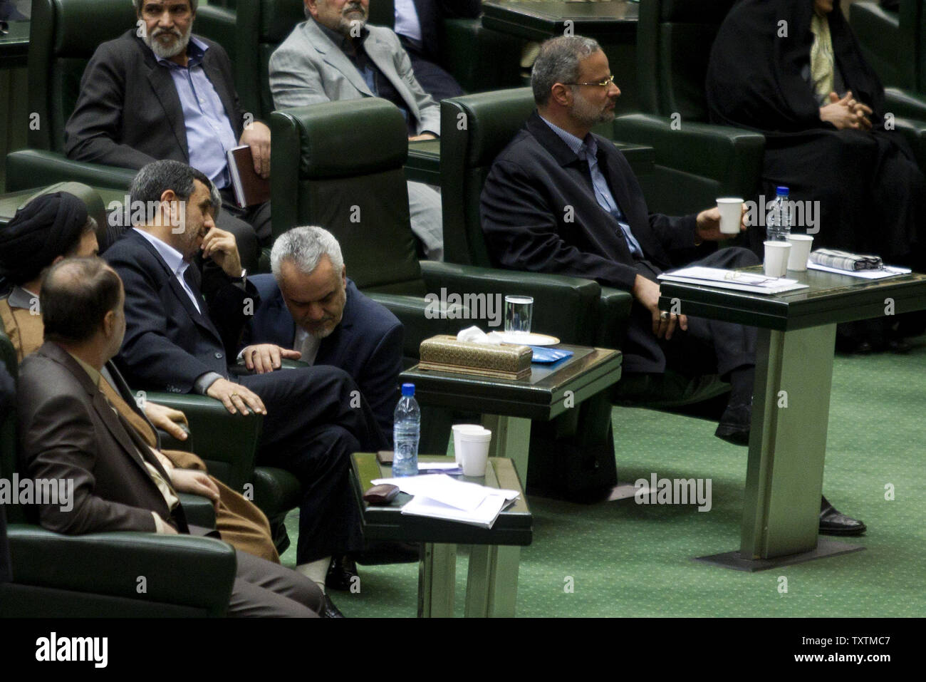 Iranian President Mahmoud Ahmadinejad (L) speaks to Vice President, Mohammad Reza Rahimi (C) during the impeachment of the labor minister , Abdolreza Sheikholeslami (R) at the parliament in Tehran, Iran on February 3, 2013. Out of 272 lawmakers in the parliament on Sunday, 192 voted against the labor minister. The main reason behind the MP's decision to dismiss the minister was Sheikholeslami's refusal  to remove former Tehran prosecutor general Saeed Mortazavi from his post as the director of the Social Security Organization.     UPI/Maryam Rahmanian Stock Photo