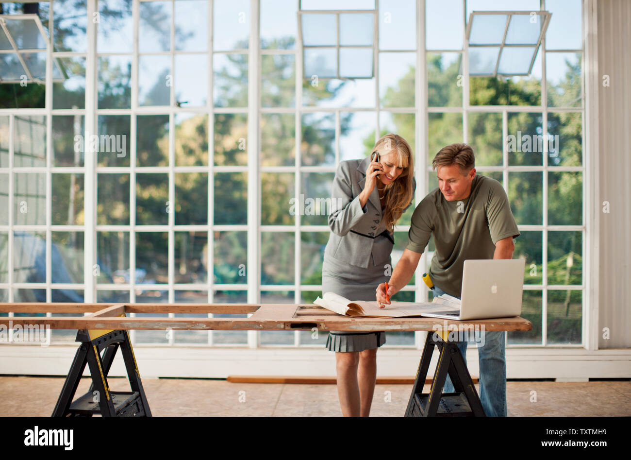 Mid adult builder making notes on a  blue print. Stock Photo